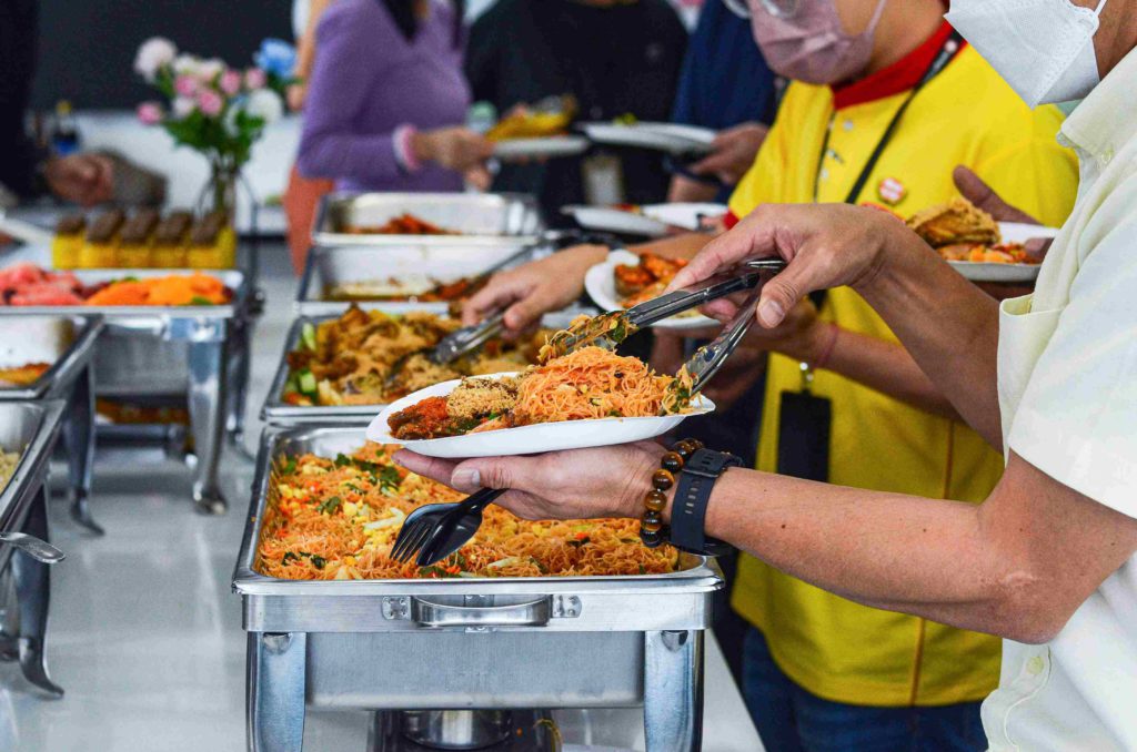 Guests wearing masks and getting food from silver trays at the office buffet catering by idocatering during 2022 COVID-19 pandemic 5