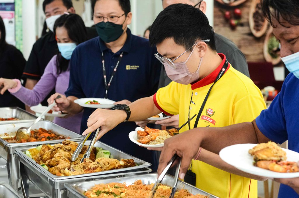 Yellow shirt guy wearing mask and getting food from silver trays at the office buffet catering by idocatering during 2022 COVID-19 pandemic 4